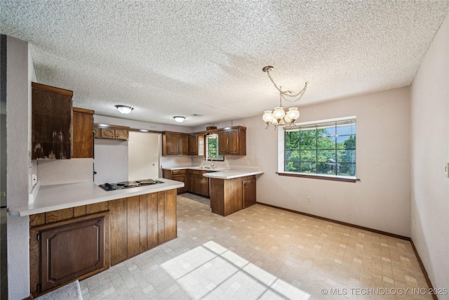 kitchen with a peninsula, black electric cooktop, a chandelier, baseboards, and a sink