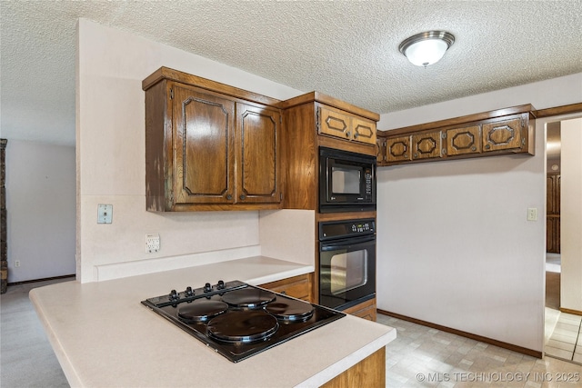 kitchen with black appliances, a textured ceiling, light countertops, brown cabinetry, and baseboards