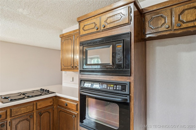 kitchen with black appliances, a textured ceiling, light countertops, a peninsula, and brown cabinets