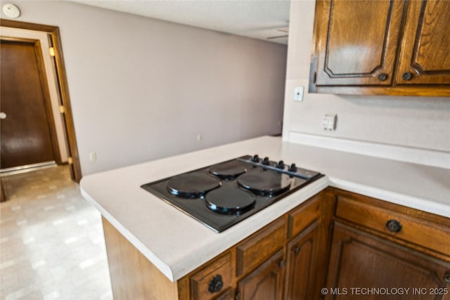 kitchen with black stovetop, light countertops, a peninsula, and light floors