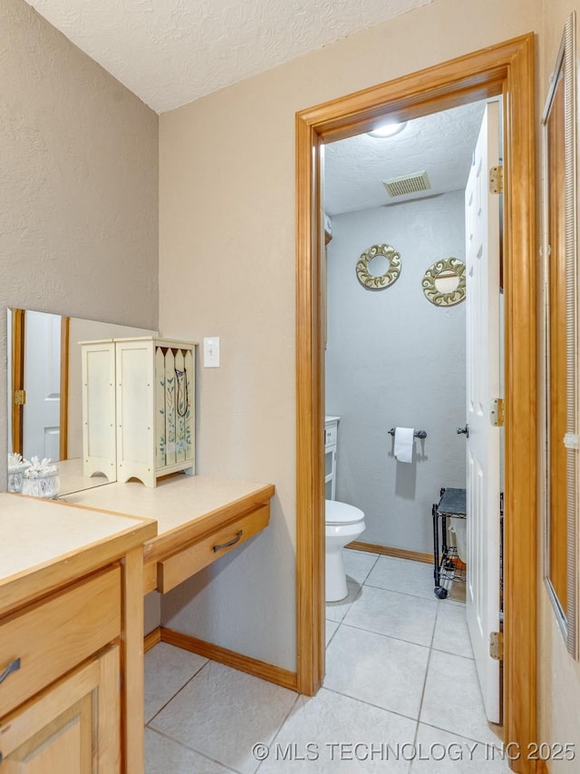 bathroom featuring toilet, tile patterned flooring, vanity, baseboards, and a textured ceiling