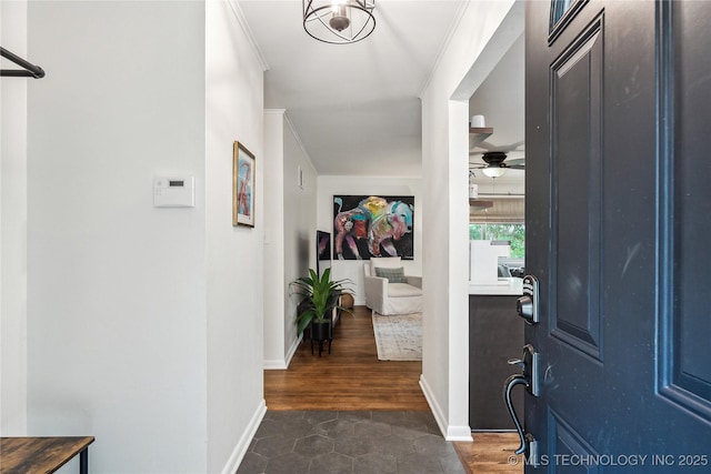 entryway featuring ornamental molding, a ceiling fan, and baseboards