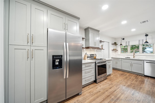 kitchen featuring appliances with stainless steel finishes, a sink, light countertops, light wood finished floors, and recessed lighting