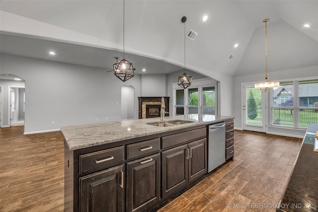 kitchen with stainless steel dishwasher, arched walkways, high vaulted ceiling, open floor plan, and dark wood finished floors