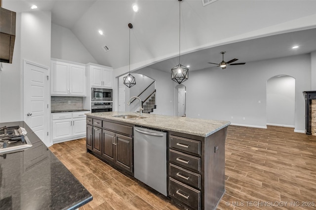 kitchen featuring stainless steel appliances, arched walkways, a sink, a ceiling fan, and white cabinets