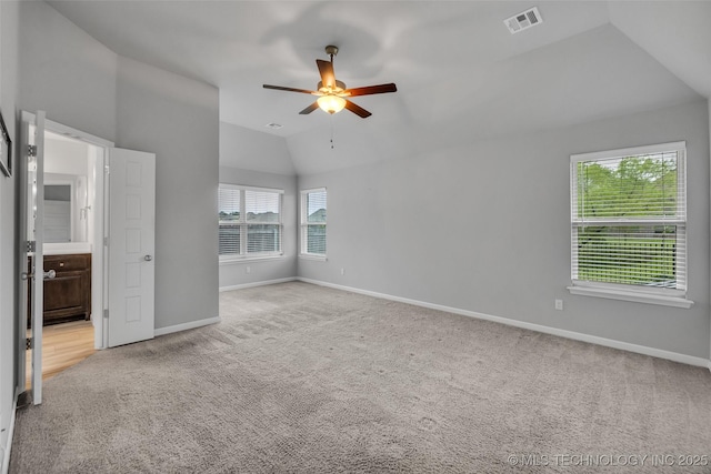 unfurnished bedroom featuring vaulted ceiling, carpet floors, baseboards, ceiling fan, and ensuite bathroom