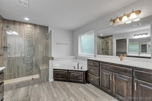 bathroom with a stall shower, vanity, a bath, and recessed lighting