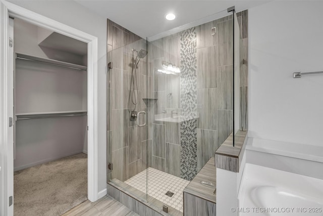 full bathroom with a stall shower, recessed lighting, a walk in closet, and baseboards