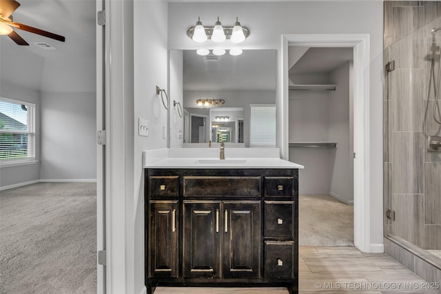 bathroom featuring ceiling fan, a shower stall, vanity, and baseboards