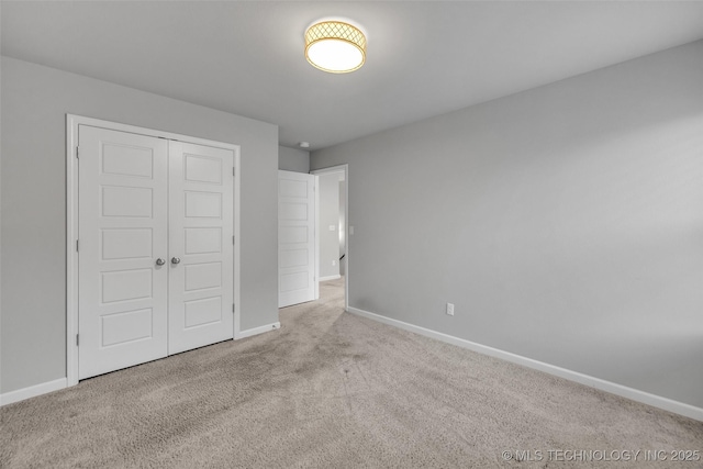 unfurnished bedroom featuring carpet, baseboards, and a closet