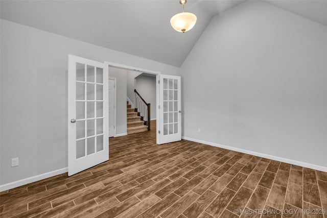 spare room featuring french doors, vaulted ceiling, dark wood-style floors, baseboards, and stairway
