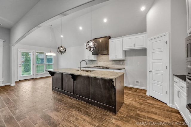 kitchen with a sink, high vaulted ceiling, white cabinetry, light stone countertops, and backsplash