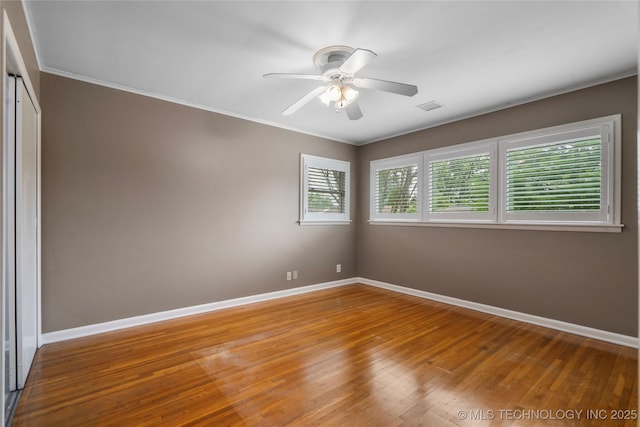 empty room with baseboards, wood finished floors, ceiling fan, and ornamental molding