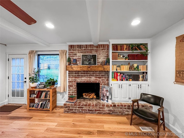 living area featuring beamed ceiling, a fireplace, wood finished floors, baseboards, and recessed lighting