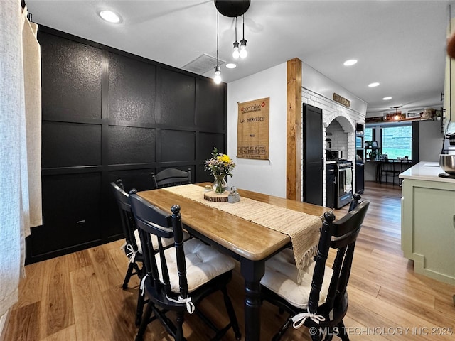 dining space featuring a decorative wall, light wood-style flooring, and recessed lighting