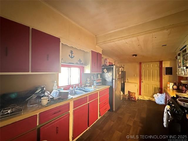 kitchen with red cabinets, freestanding refrigerator, dark wood-type flooring, a sink, and black range with gas cooktop
