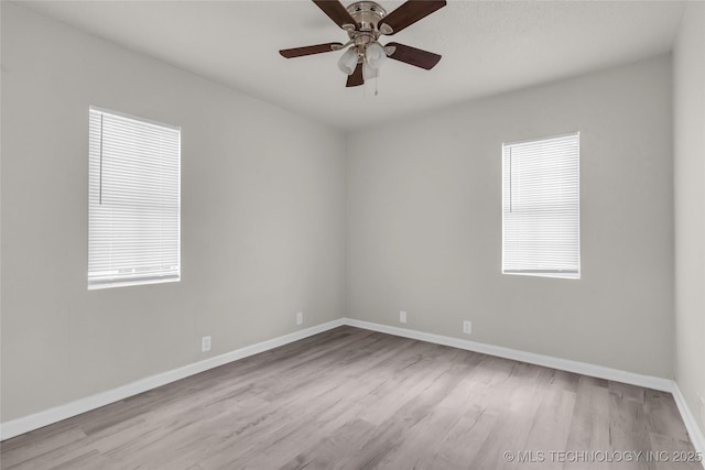 spare room with wood finished floors, healthy amount of natural light, and baseboards