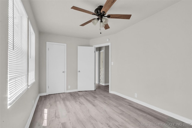 unfurnished bedroom featuring multiple windows, light wood-type flooring, baseboards, and ceiling fan