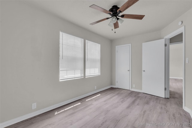 unfurnished bedroom with wood finished floors, multiple windows, baseboards, and a ceiling fan