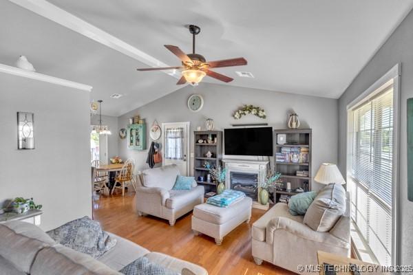 10718 W 162nd St, Skiatook, OK 74070 - living room with wood finished floors, vaulted ceiling, a ceiling fan, a fireplace, and a chandelier