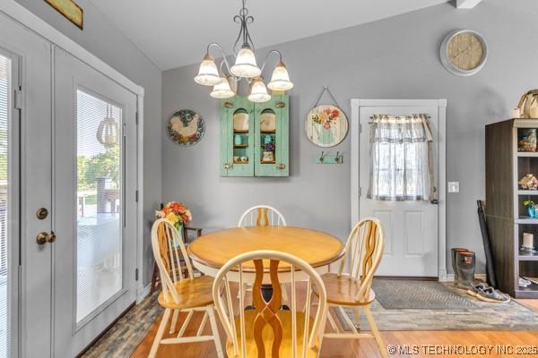 10718 W 162nd St, Skiatook, OK 74070 - dining space with wood finished floors, plenty of natural light, a chandelier, baseboards, and vaulted ceiling