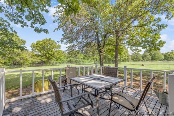 10718 W 162nd St, Skiatook, OK 74070 - wooden deck featuring outdoor dining space, a lawn, and view of wooded area