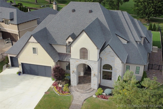 view of front of property featuring a shingled roof, stone siding, driveway, and a standing seam roof