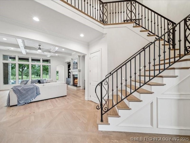 4301 S Mimosa Ave, Broken Arrow, OK 74011 - staircase with a ceiling fan, recessed lighting, a warm lit fireplace, coffered ceiling, and baseboards