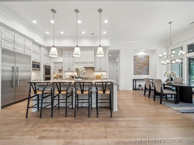 4301 S Mimosa Ave, Broken Arrow, OK 74011 - kitchen with built in appliances, light wood finished floors, a kitchen bar, a chandelier, and crown molding