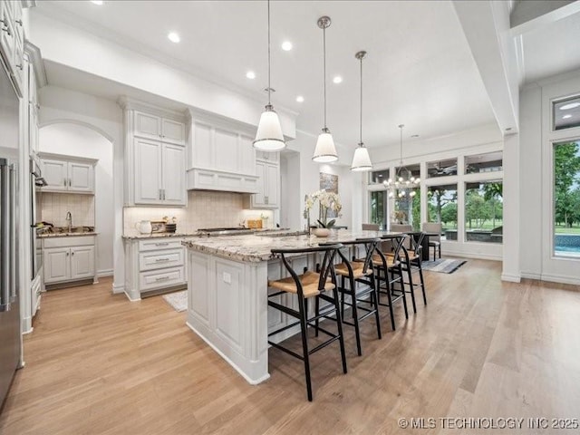 4301 S Mimosa Ave, Broken Arrow, OK 74011 - kitchen with light wood-style flooring, a large island, tasteful backsplash, a sink, and recessed lighting
