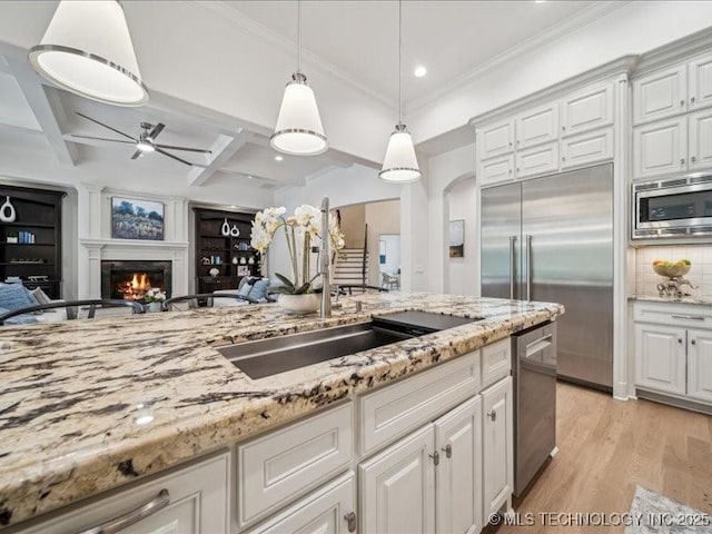 4301 S Mimosa Ave, Broken Arrow, OK 74011 - kitchen featuring built in appliances, a lit fireplace, white cabinets, light wood finished floors, and coffered ceiling