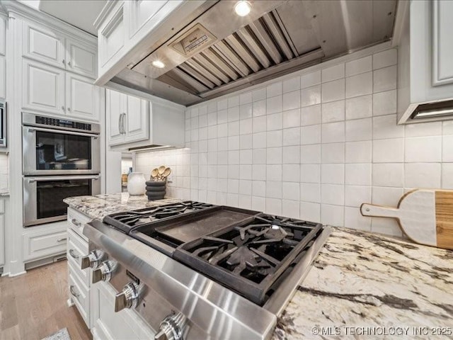 4301 S Mimosa Ave, Broken Arrow, OK 74011 - kitchen with stainless steel appliances, custom range hood, white cabinetry, and tasteful backsplash