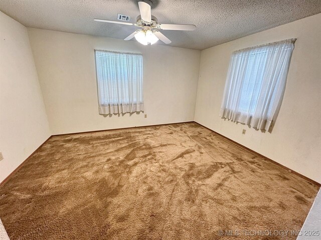 spare room featuring a textured ceiling, carpet flooring, a ceiling fan, and plenty of natural light