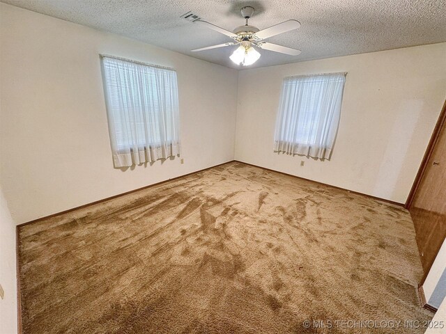 unfurnished room with carpet flooring, healthy amount of natural light, a ceiling fan, and a textured ceiling