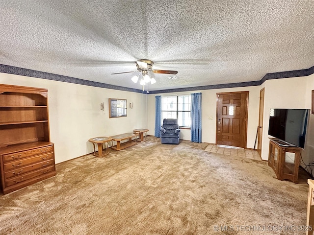 sitting room with carpet, a ceiling fan, a textured ceiling, and crown molding