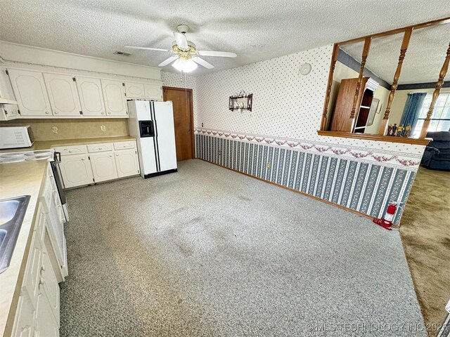kitchen with white appliances, wallpapered walls, a ceiling fan, white cabinets, and light countertops