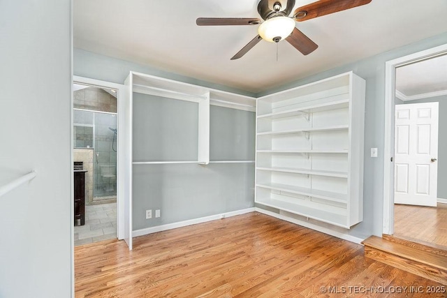 unfurnished bedroom with wood finished floors, baseboards, connected bathroom, and ceiling fan
