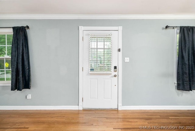 entrance foyer with wood finished floors, ornamental molding, baseboards, and healthy amount of natural light