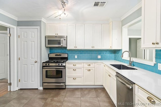 kitchen with stainless steel appliances, a sink, light countertops, white cabinetry, and ornamental molding