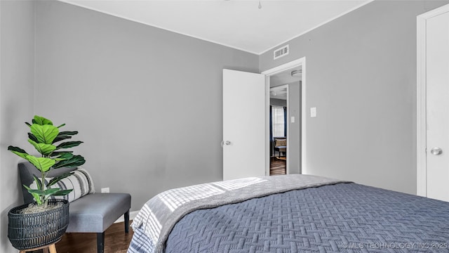 bedroom with wood finished floors and crown molding