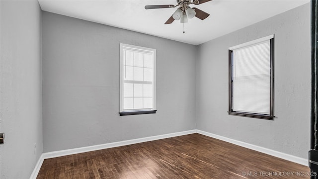 spare room featuring dark wood-style floors, ceiling fan, and baseboards