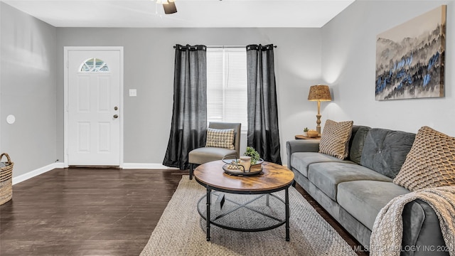 living area featuring dark wood-type flooring, a ceiling fan, and baseboards