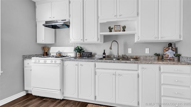 kitchen featuring under cabinet range hood, gas range gas stove, a sink, white cabinetry, and dark wood-style flooring