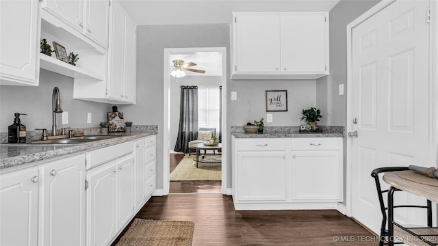 kitchen with a sink, dark wood finished floors, white cabinets, a ceiling fan, and open shelves