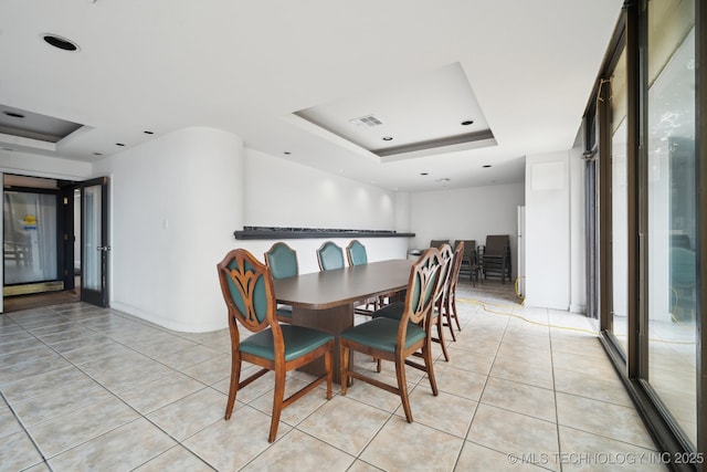 dining area featuring a raised ceiling and light tile patterned flooring