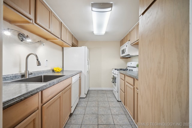 kitchen featuring white appliances, a sink, dark countertops, light tile patterned flooring, and light brown cabinets