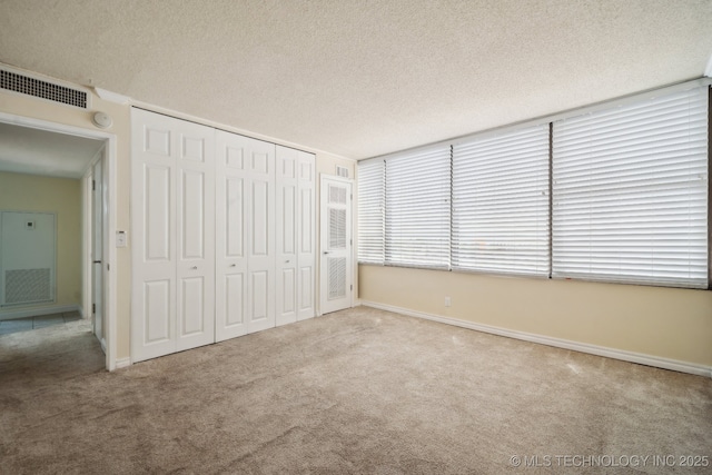 unfurnished bedroom featuring carpet, a textured ceiling, a closet, and baseboards