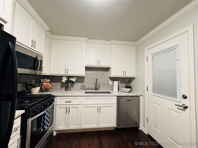 3922 S Norfolk Ave, Tulsa, OK 74105 - kitchen with appliances with stainless steel finishes, a sink, white cabinets, backsplash, and dark wood-type flooring