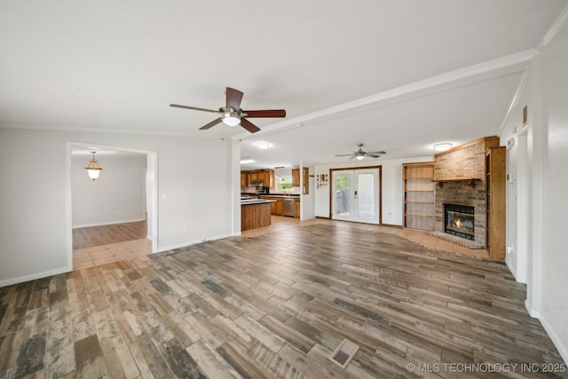 11462 Red Fox Ln, Sperry, OK 74073 - unfurnished living room with a brick fireplace, dark wood-type flooring, ceiling fan, baseboards, and ornamental molding