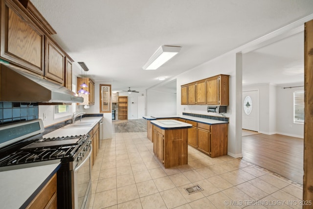 11462 Red Fox Ln, Sperry, OK 74073 - kitchen with stainless steel gas stove, under cabinet range hood, a ceiling fan, a sink, and brown cabinetry